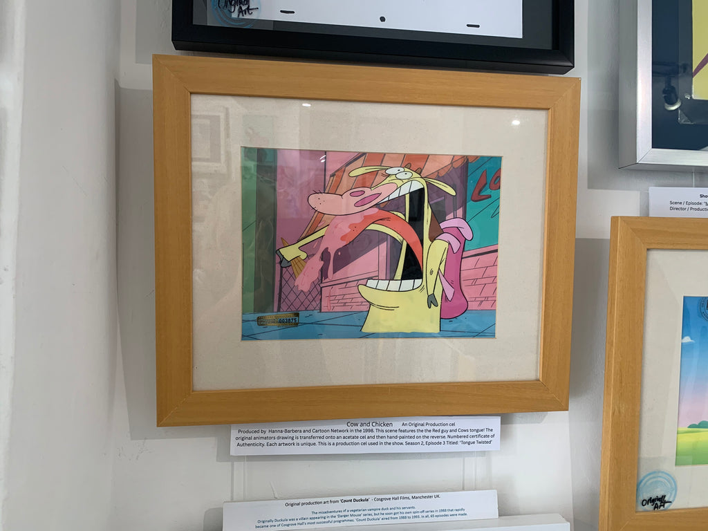 A framed original animation production from Nickelodeon's 'COW AND CHICKEN' Show, featuring a colourful cartoon cel mounted in a light wood frame with a white mat, displayed on a gallery wall.