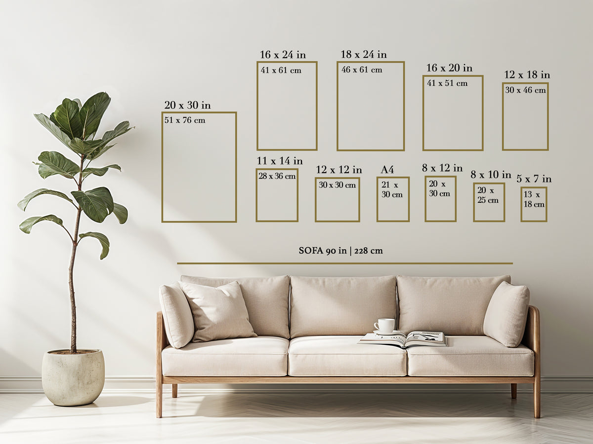 A styled living room scene showing a beige sofa against a white wall, with a potted fiddle-leaf fig plant on the left and a set of wall-sized photo frame size diagrams above the couch. The diagrams include dimensions for various frame shapes and sizes, with one labeled SOFA 90 in | 228 cm.